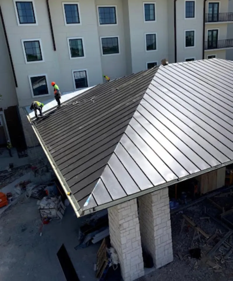 Crew installing standing seam metal roof panels on a commercial project in Greenfield